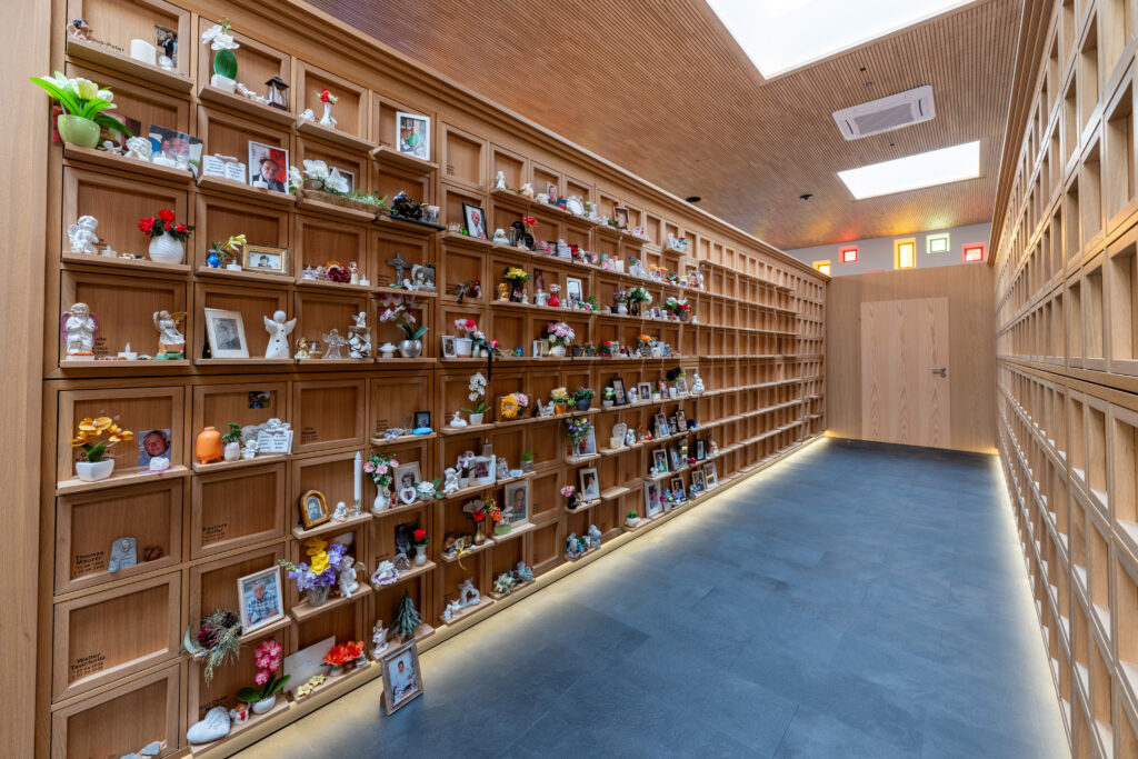 Lindemann-Kolumbarium mit Holzregalen und Urnen in Reihengräbern.